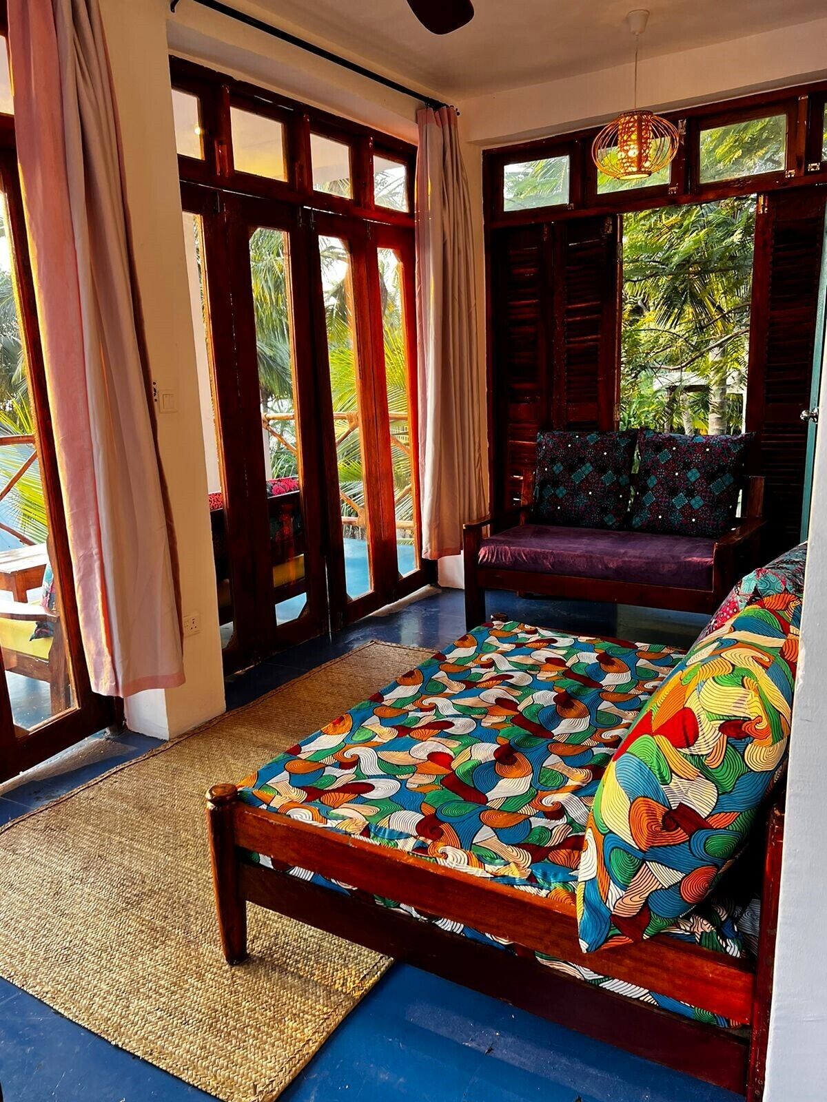 A room with a bed, a bench, and large windows.