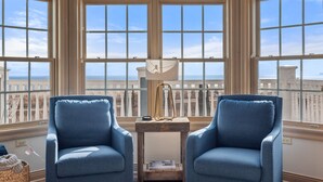 A room with two blue armchairs, a wooden side table, and a view of the city through large windows. - Beach front luxury spacious villa ! (Sheboygan)