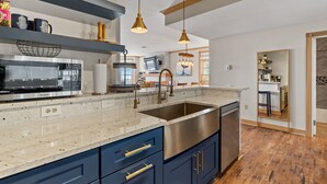A modern kitchen with a stainless steel sink, blue cabinets, and a marble countertop. - Beach front luxury spacious villa ! (Sheboygan)