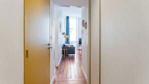 Un pasillo con piso de madera que conduce a una sala de estar con un sofá y televisor.