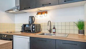 Cocina moderna con microondas, hervidor, lavabo y una planta en maceta.