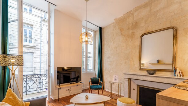 Una sala de estar moderna con televisor de pantalla plana, chimenea, comedor y balcón con vistas a la ciudad.