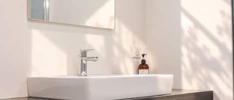 A bathroom with a white sink, a chrome faucet, and a bottle of soap on the counter.