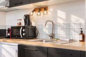 A kitchen with a microwave, coffee maker, and a bottle of liquid soap. - Charming and radiant flat of 55 m² located in the heart of Bordeaux (Bordeaux)