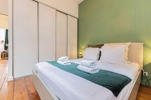 A hotel room with a bed, a green wall, and a sliding door.