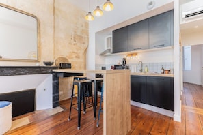 A modern kitchen with a central island, bar stools, and a stone accent wall.