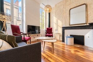 A modern living room with a fireplace, wooden flooring, and a large mirror. - Charming and radiant flat of 55 m² located in the heart of Bordeaux (Bordeaux)