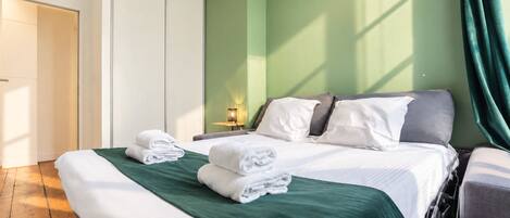Habitación de hotel con cama, mesita de noche, lámpara y vistas al exterior.