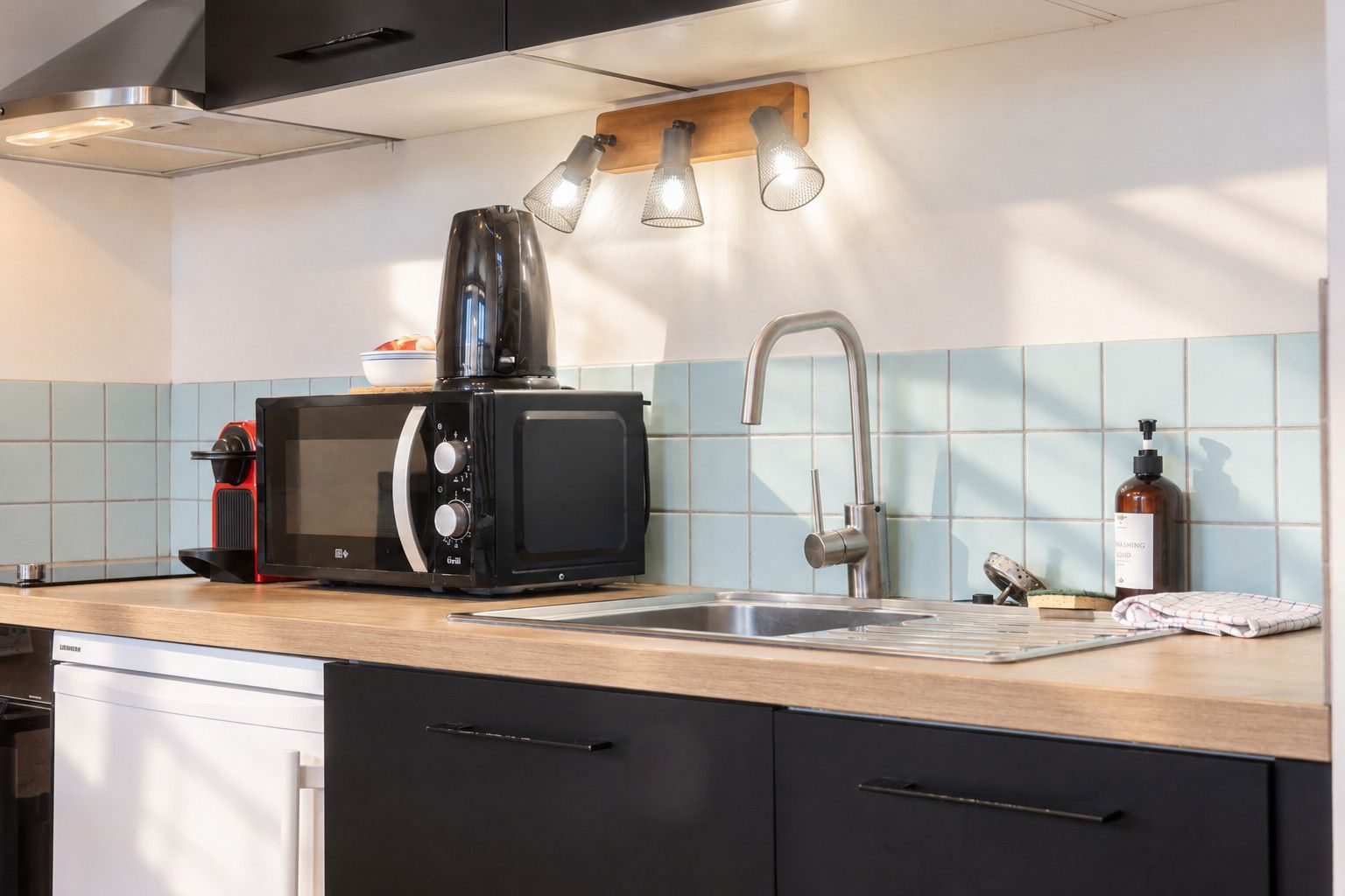 A modern kitchen with a built-in microwave, a coffee maker, a sink, and a wooden countertop.
