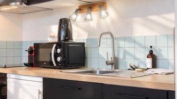 A modern kitchen with a built-in microwave, a coffee maker, a sink, and a wooden countertop.