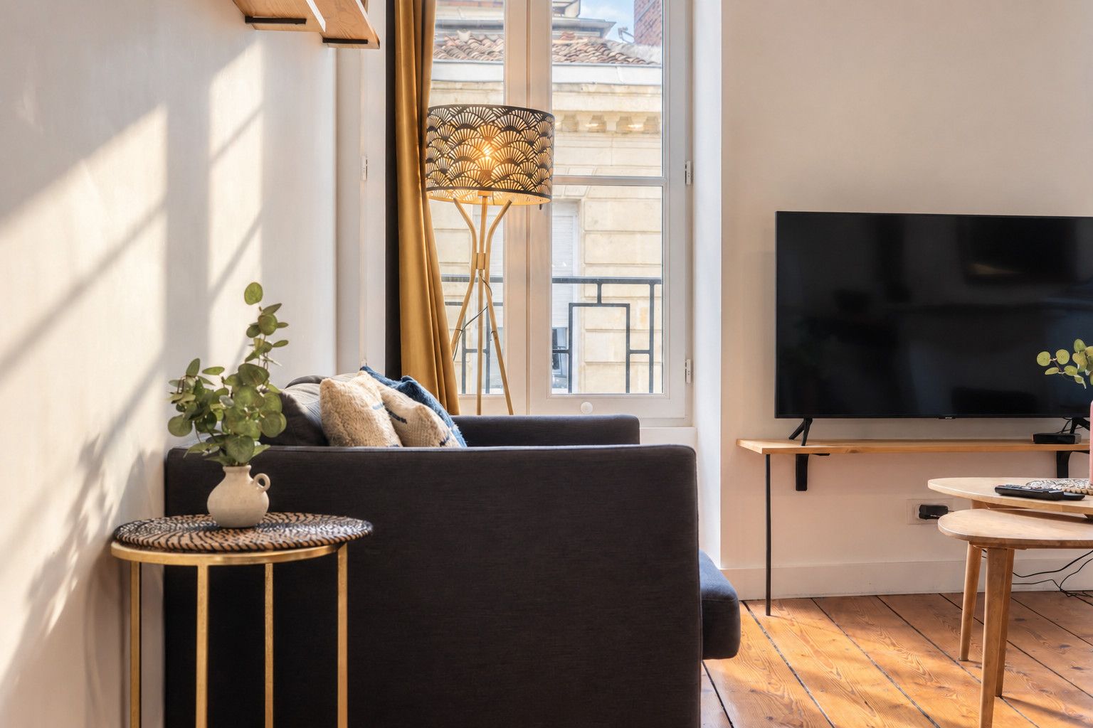 A modern living room with a sofa, a TV, a small table, and a floor lamp.