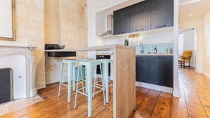 A modern kitchen with a central island, bar stools, and a wooden floor.