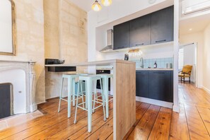 Une cuisine moderne avec un îlot central, des tabourets de bar et un plancher en bois.