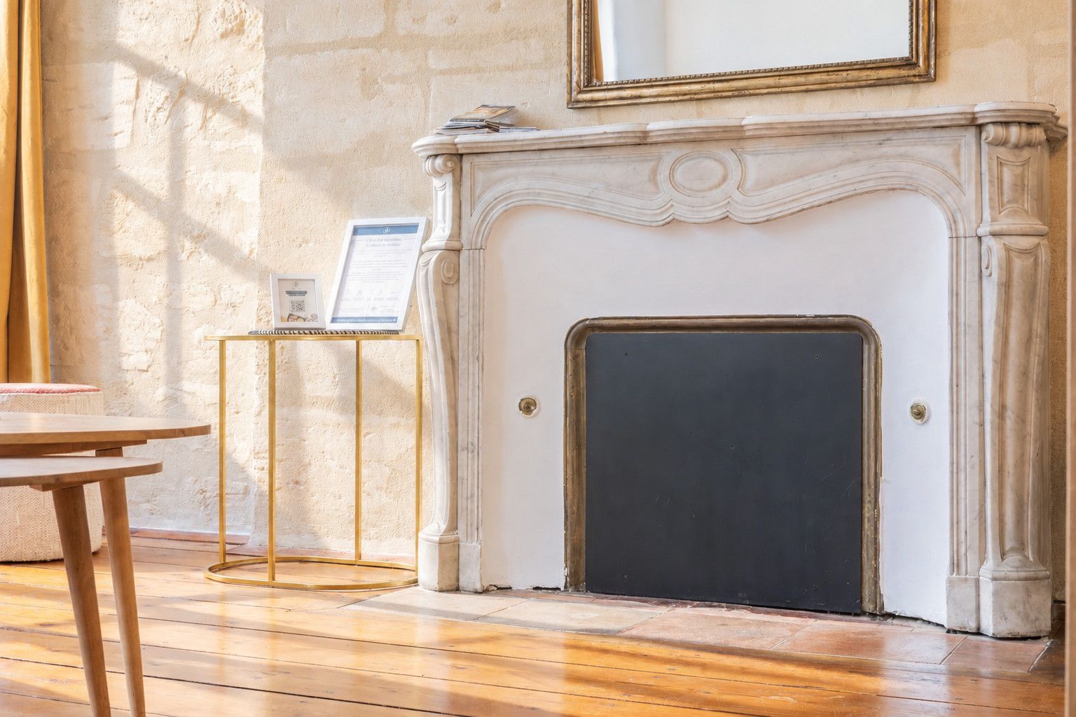 Una habitación con chimenea, una mesa de madera y un certificado en un atril.