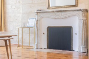 Een kamer met een open haard, een ronde houten tafel en een gecertificeerd document op een standaard.