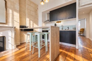 Une cuisine moderne dotée d’un îlot central, de tabourets de bar et d’un four encastré.