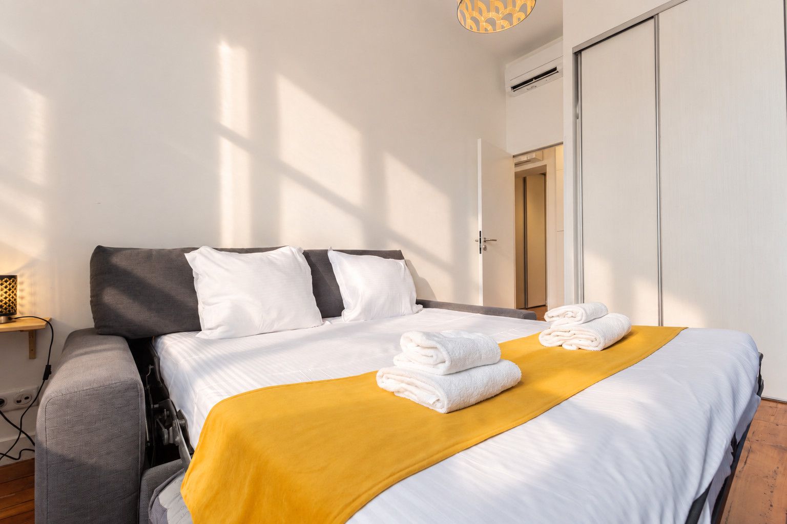 Una habitación de hotel con cama, mesita de noche, lámpara y armario.