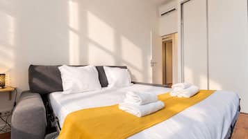 Una habitación de hotel con cama, mesita de noche, lámpara y armario.