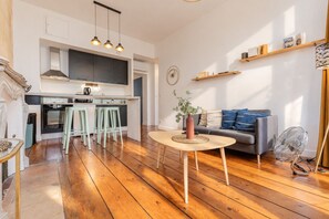 Eine moderne Küche mit Barhocker, einem Esstisch und einer Wohnbereicks mit einer Couch und einem Ventilator.