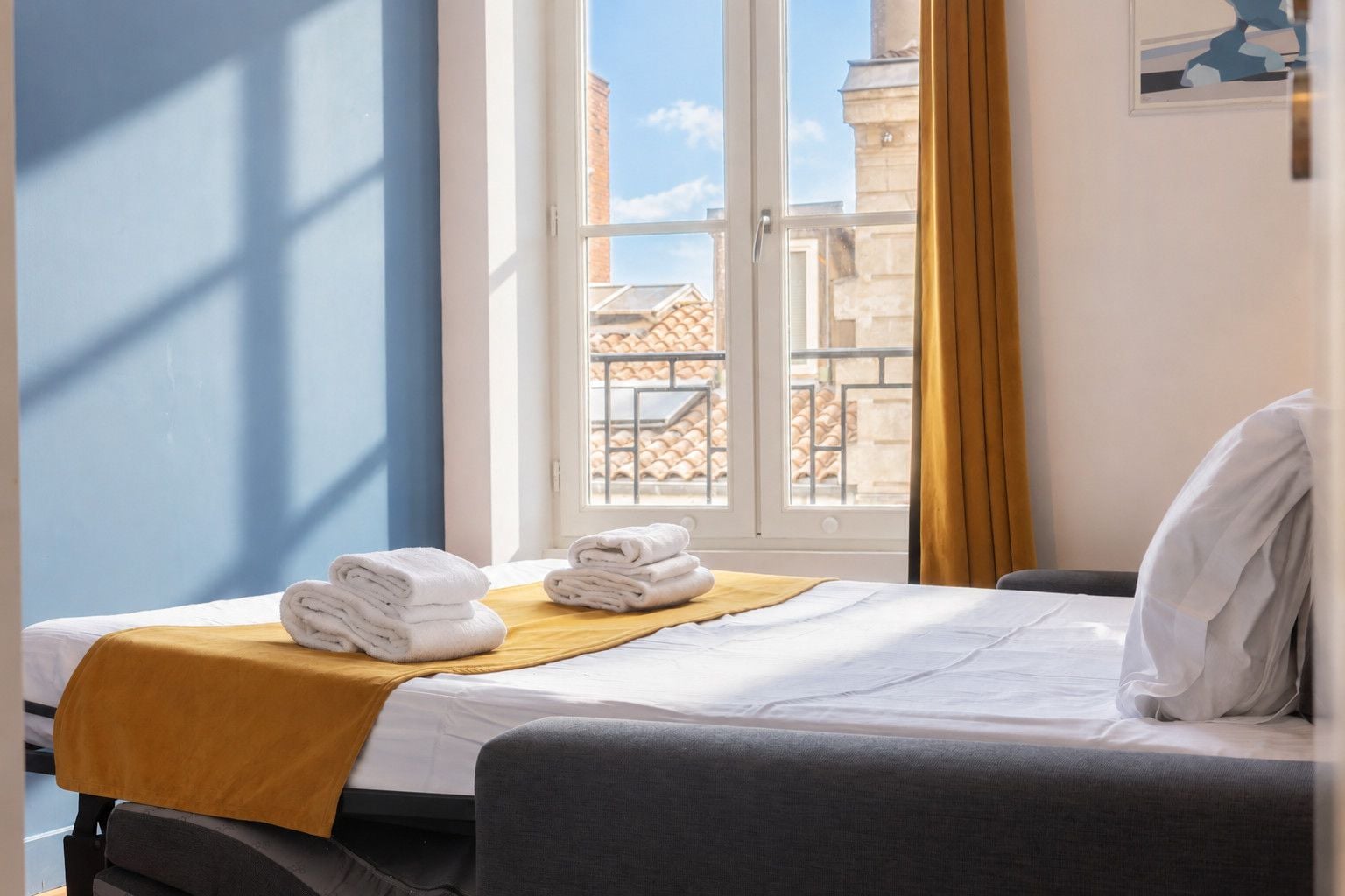 Ein Hotelzimmer mit Bett, Fenster mit Blick auf Gebäude und Handtüchern auf dem Bett.