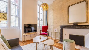 Ein modernes Wohnzimmer mit einem Flachbildfernseher, einem roten Sessel, einem kleinen Tisch und einem Kamin.