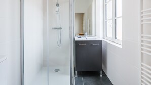 A modern bathroom with a glass-enclosed shower, a sink, and a mirror.
