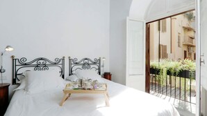 A bed with a tray of breakfast items, a black wrought iron headboard, and a view of a balcony with plants. - ROMAC Leone V Unique 5-bdr near the Spanish Steps (Roma)
