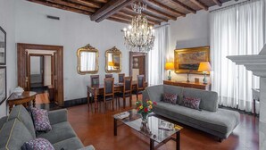 A spacious living room with a chandelier, a sofa, a coffee table, and a dining area with chairs and a table. - ROMAC Leone V Unique 5-bdr near the Spanish Steps (Roma)