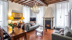 A living room with a fireplace, a sofa, a dining table, and a chandelier. - ROMAC Leone V Unique 5-bdr near the Spanish Steps (Roma)