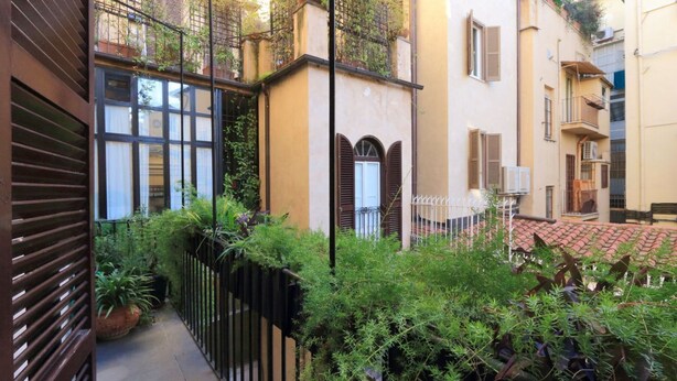 A narrow alleyway with a black metal fence, potted plants, and buildings with balconies and shutters. - ROMAC Leone V Unique 5-bdr near the Spanish Steps (Roma)