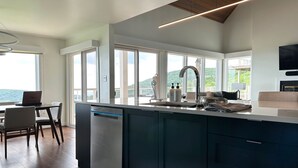 A modern kitchen with a built-in dishwasher, a large island with a sink, and a dining area with a table and chairs. - Sauna, dog friendly Amazing views to ski slopes (Wintergreen Resort)
