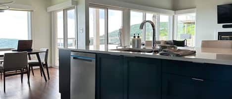A modern kitchen with a built-in dishwasher, a large island with a sink, and a dining area with a table and chairs.