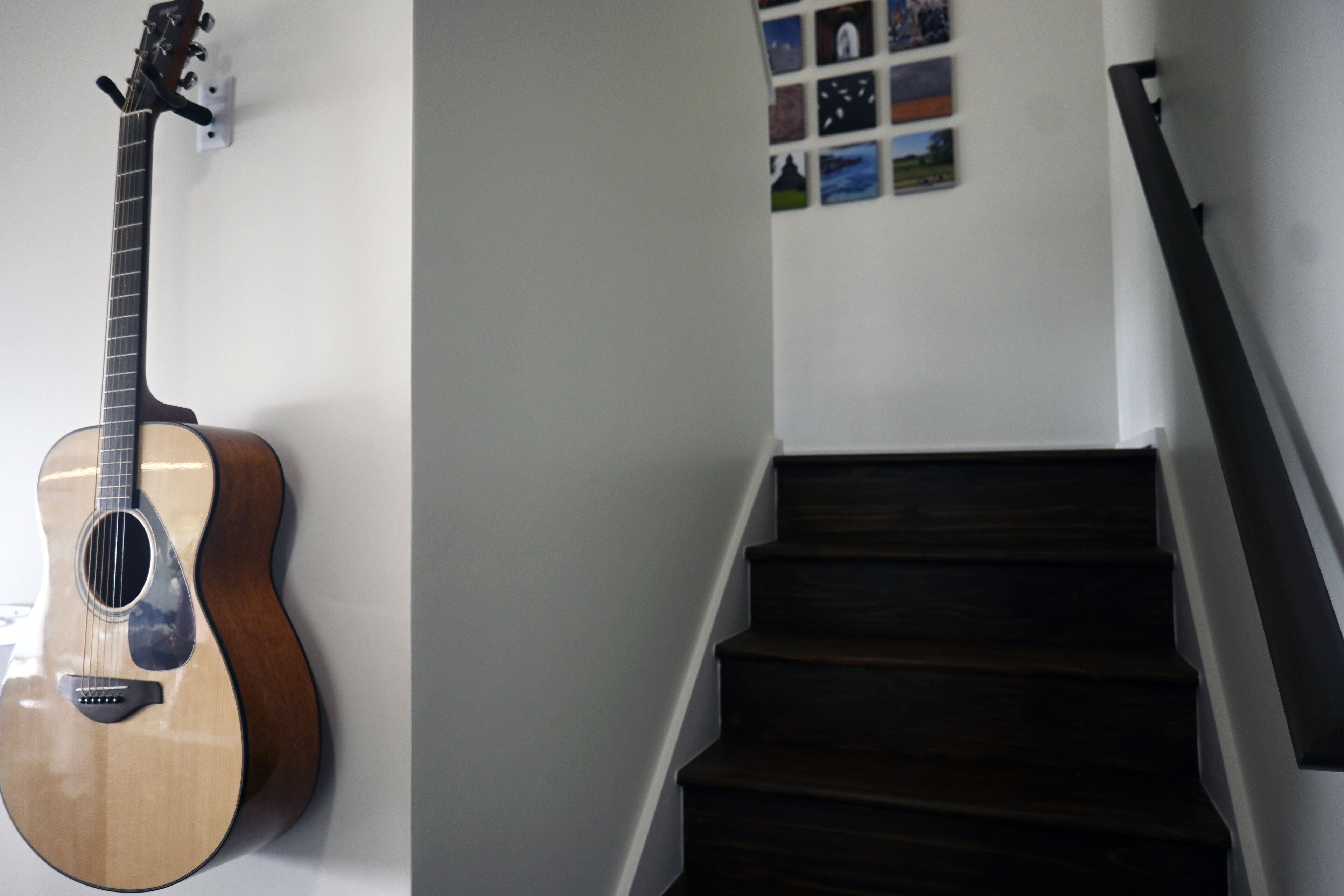 A staircase with dark wooden steps and a wall-mounted guitar.