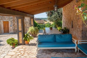 A covered outdoor seating area with stone walls, a wooden ceiling, and potted plants. - SA FRANQUESA VELLA - ANTONI I CATALINA CANONGE -Charming apartment in agritourism (Vilafranca de Bonany)