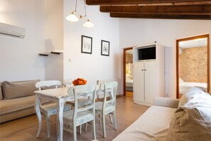 A modern living room with a dining area, a sofa, a TV cabinet, and a stone wall. - SA FRANQUESA VELLA - ANTONI I CATALINA CANONGE -Charming apartment in agritourism (Vilafranca de Bonany)