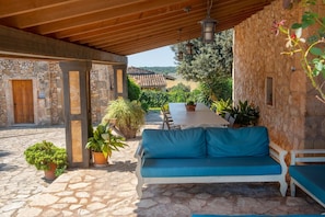 Un espace extérieur abrité, doté de murs en pierre, d’un plafond en bois et de plantes en pot.