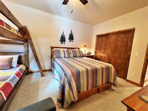 A bedroom with a bunk bed, a single bed, and a wooden door.