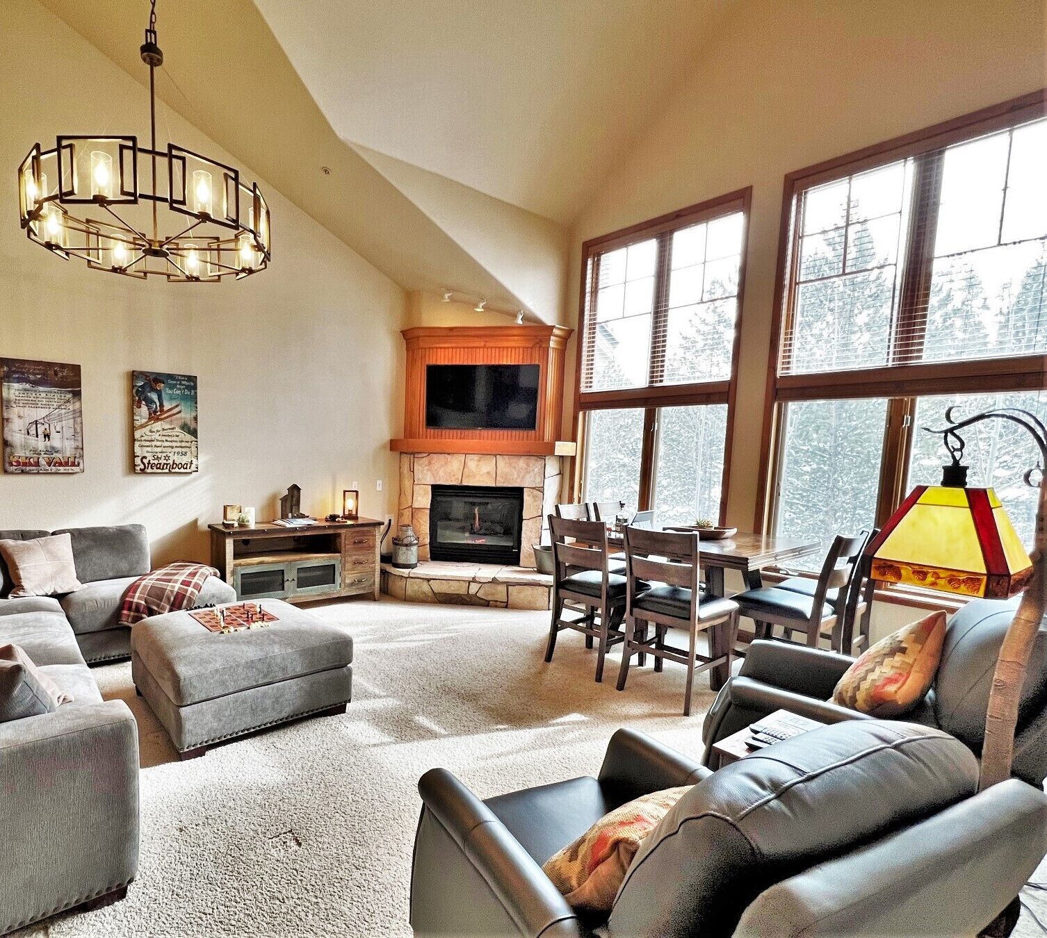A spacious living room with a fireplace, a dining area, and a large window providing a view of the outdoors.