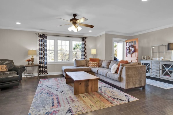 A living room with a sofa, a coffee table, a TV, and a ceiling fan. - Tiger Walk - 3 Miles from Death Valley! (Clemson)