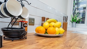 A kitchen with a plate of oranges and lemons, a coffee machine, and a knife set on the counter. - Stunning 2-Bed Apartment in Purley - Croydon Gem (Purley)