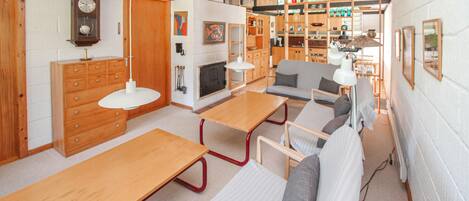 A modern interior with a wooden dining table, a sofa, and a kitchen area with wooden cabinets and a stove.