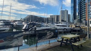 A marina with boats docked, a modern building, and a bench.