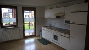 A kitchen with white cabinets, a stove, a sink, and a window overlooking a garden. - Vacation apartment with 50 square meters - at Gästehaus Kunz in Rust (Rust)