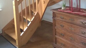 A wooden staircase with a wooden dresser and a lantern in a room with tiled flooring. - Vacation apartment with 50 square meters - at Gästehaus Kunz in Rust (Rust)