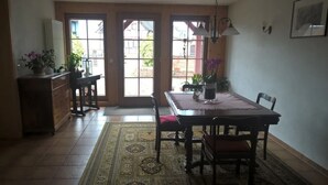 A dining area with a table, chairs, a rug, and a view through large windows. - Vacation apartment with 50 square meters - at Gästehaus Kunz in Rust (Rust)