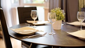 A dining table set with plates, cutlery, and wine glasses, with a potted plant on the table. - Apartment 'Amselnest' with Private Terrace, Private Garden (Kempten)