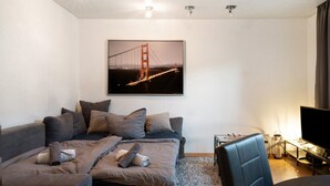 A modern living room with a sofa, a television, and a framed picture of a bridge. - Apartment 'Amselnest' with Private Terrace, Private Garden (Kempten)