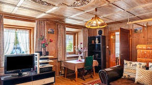 Un intérieur en bois comprenant une télévision, une table à manger, des chaises et un canapé.