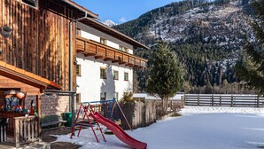 Un bâtiment en bois avec un toboggan rouge, un mur en briques et une montagne enneigée en arrière-plan.