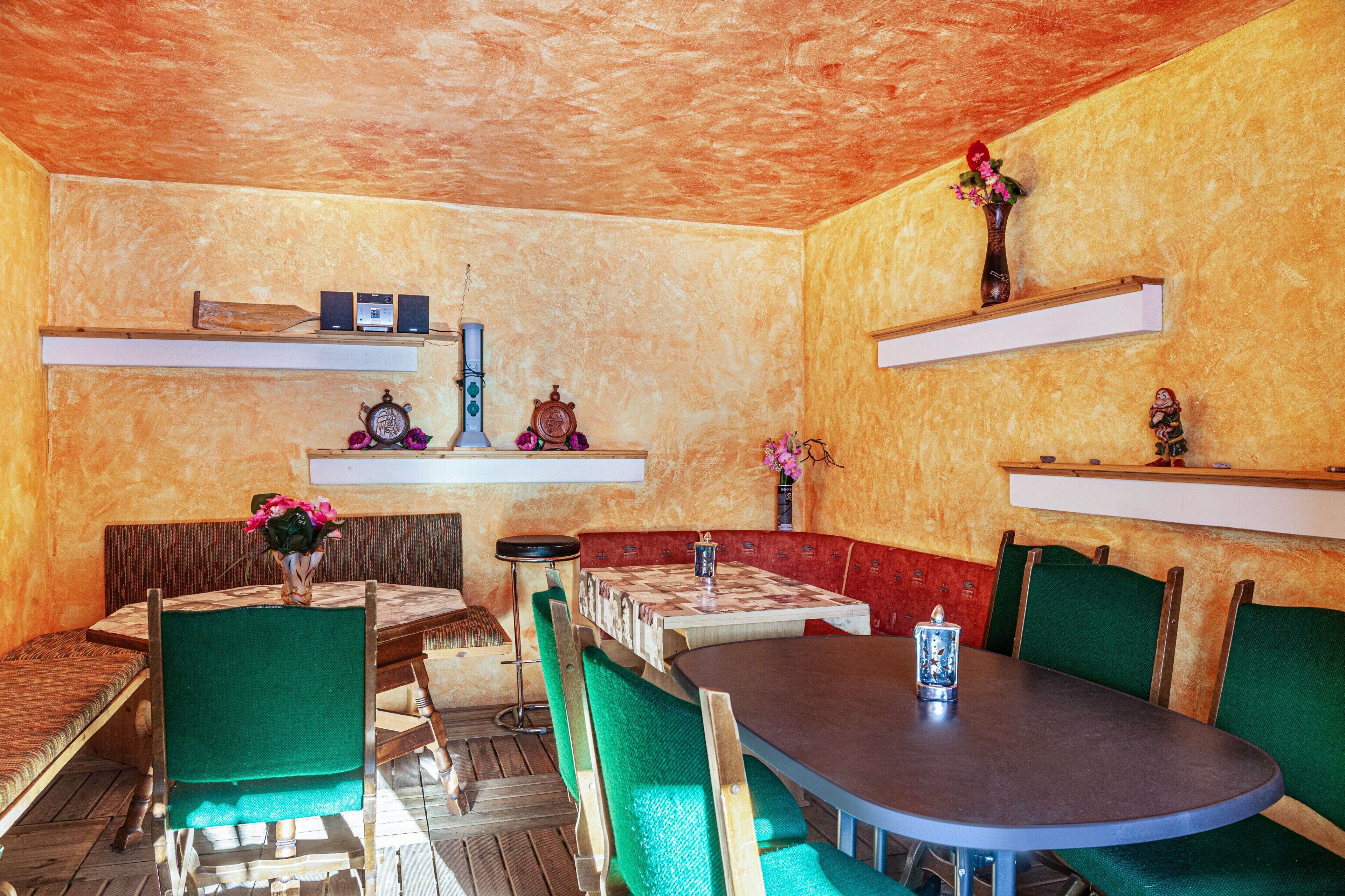 A restaurant with a wooden table, green upholstered chairs, and a red cushioned bench.
